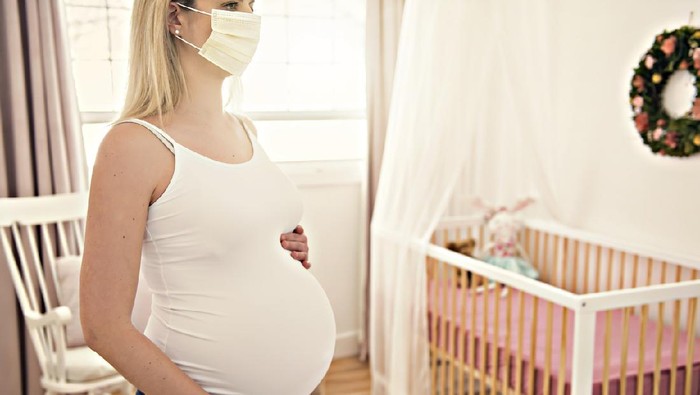 A pregnant woman wears a surgical mask to protect a COVID-19 (Coronavirus) and PM 2.5 and show a surgical mask on the abdomen to prevent infection to the fetus.