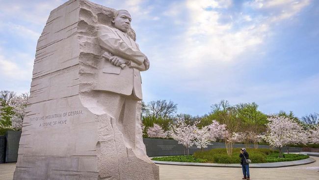 Washington DC, USA - April 12, 2015: A man photographs the Martin Luther King Jr. Memorial during spring season in West Potomac Park. The work was created by Lei Yixin and opened to the public August 22, 2011.