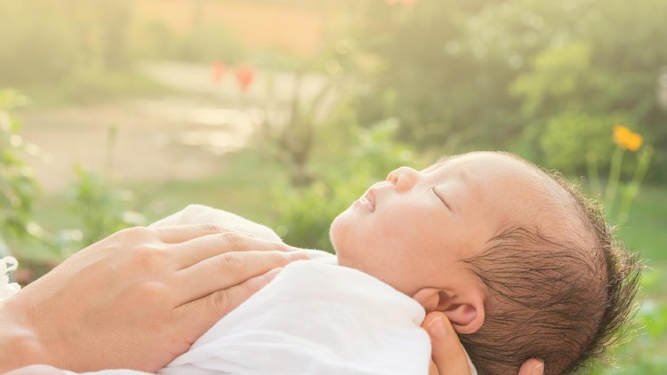 Baby sleeps on mother's hands and morning sun