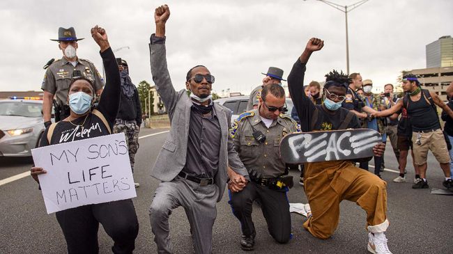 Demonstrators including Abimbola Oretadu, second from left, and David Walker kneel with Connecticut State Trooper Maurice, no first name available, after hundreds of demonstrators closed I84 during a march Monday, June 1, 2020, in Hartford, Conn., in response to the May 25, 2020, killing of George Floyd at the hands of Minneapolis police officers. Walker, 22, a US Army veteran, said he was scared before kneeling with the trooper because 