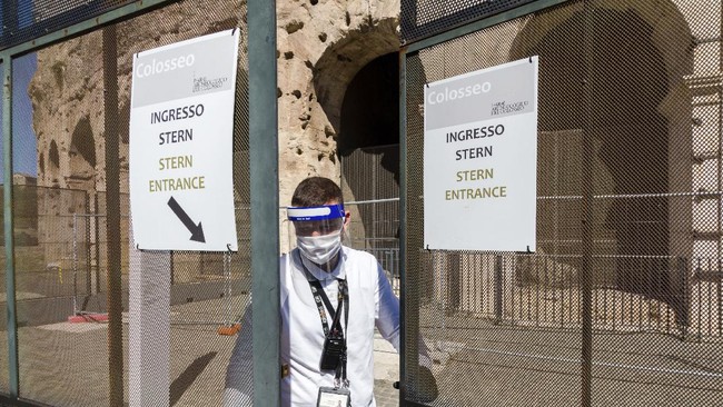 A member of the staff closes one of the gates of the Colosseum in Rome, Monday, June 1, 2020, during a press conference announcing the reopening to the public of one of Italy's most visited monument, after more of two months of lockdown for the coronavirus pandemics. The Colosseum, Palatine, Roman Forum and Domus Aurea reopens to the public on 1 June with some access restrictions for visitors. (AP Photo/Domenico Stinellis)