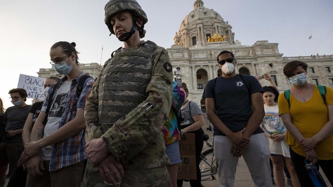 First Lt. Andrea Drost of the Minnesota Army National Guard joins protesters in a moment of prayer at the State Capitol in St. Paul, Minn., Monday, June 1, 2020, during protests over the death of George Floyd, who died May 25 after being restrained by Minneapolis police. (Carlos Gonzalez/Star Tribune via AP)