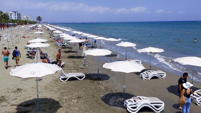 People gather at Mackenzie beach in the coastal city of Larnaca on the Mediterranean island of Cyprus on May 23, 2020. - A new form of beach life, spaced apart, emerged on the Mediterranean holiday island of Cyprus after more than two months of coronavirus-imposed curbs were lifted on freedom of movement. (Photo by Etienne TORBEY / AFP) / The erroneous mention[s] appearing in the metadata of this photo by Adel AL SALMAN has been modified in AFP systems in the following manner: [Etienne Torbey] instead of [Adel Al-Salman]. Please immediately remove the erroneous mention[s] from all your online services and delete it (them) from your servers. If you have been authorized by AFP to distribute it (them) to third parties, please ensure that the same actions are carried out by them. Failure to promptly comply with these instructions will entail liability on your part for any continued or post notification usage. Therefore we thank you very much for all your attention and prompt action. We are sorry for the inconvenience this notification may cause and remain at your disposal for any further information you may require.