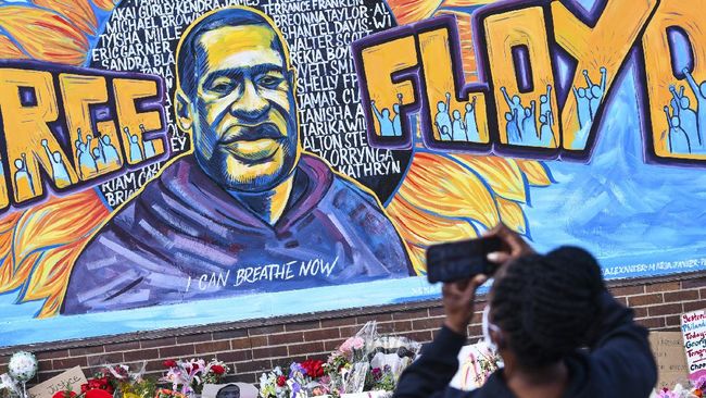 A person takes photographs of a mural in memory of George Floyd with flowers and other memorial items below, on a wall of the Cup Foods store at the corner of Chicago Avenue and East 38th Street, Friday, May 29, 2020, in Minneapolis. Protests over the death of Floyd in Minneapolis police custody have spread to other areas across the United States. (Dave Schwarz/St. Cloud Times via AP)