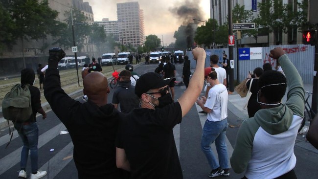 Protesters react in front of a police line as a barricade burns during a demonstration Tuesday, June 2, 2020 in Paris. Paris riot officers fired tear gas as scattered protesters threw projectiles and set fires at an unauthorized demonstration against police violence and racial injustice. Several thousand people rallied peacefully for two hours around the main Paris courthouse in homage to George Floyd and to Adama Traore, a French black man who died in police custody. (AP Photo/Michel Euler)