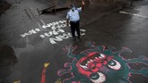 Seni Jalanan Dalam tawa dan harapan An Indian traffic policeman stands next to an artwork displayed on a road to create awareness about coronavirus during lockdown in Gauhati, India, Wednesday, April 15, 2020. (AP Photo/Anupam Nath)