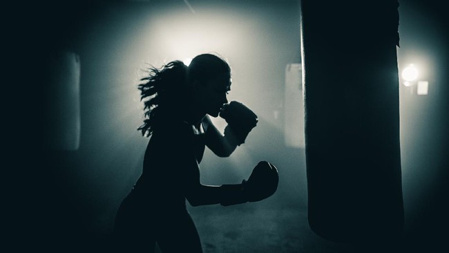 Young woman  boxer with dramatic lighting