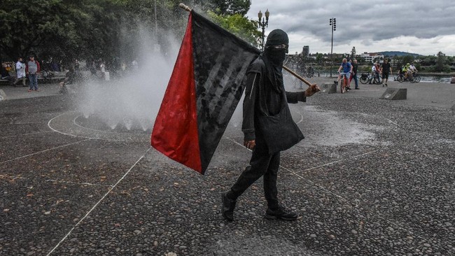 PORTLAND, OR - AUGUST 17: Members of Antifa pass a fountain during an alt-right rally on August 17, 2019 in Portland, Oregon. Anti-fascism demonstrators gathered to counter-protest a rally held by far-right, extremist groups.   Stephanie Keith/Getty Images/AFP