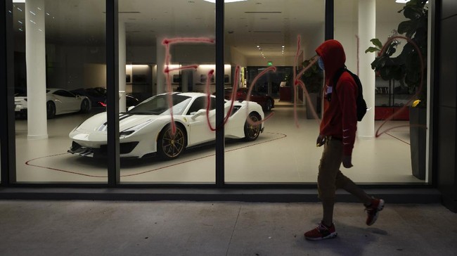 Protester melewati dealer Ferrari yang telah dicoret massa aksi kematian George Floyd pada 31 Mei.

A protester walks past graffiti in the window of Ferrari car dealer during a demonstration in response to the recent death of George Floyd in police custody in Minneapolis, in Miami, Florida on May 31, 2020. - Thousands of National Guard troops patrolled major US cities  after five consecutive nights of protests over racism and police brutality that boiled over into arson and looting, sending shock waves through the country. The death Monday of an unarmed black man, George Floyd, at the hands of police in Minneapolis ignited this latest wave of outrage in the US over law enforcement's repeated use of lethal force against African Americans -- this one like others before captured on cellphone video. (Photo by Eva Marie UZCATEGUI / AFP)