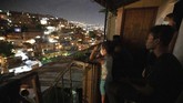 Layar Tancep, Pelipur Lara Kala Pandemi di Caracas People watch the movie Aladdin projected across the street on the roof of a home, left, in the Petare neighborhood of Caracas, Venezuela, late Monday, June 1, 2020. A neighborhood group called The Download Zone set up the movie as a free entertainment option for families cooped up since mid-March under the COVID-19 quarantine. (AP Photo/Ariana Cubillos)