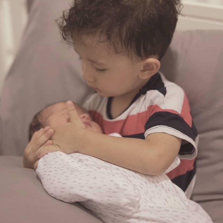 <p>James merupakan anak sulung yang sudah menunjukkan rasa sayang pada adiknya sejak kecil, Bunda. Seperti di foto ini, ia memeluk Iona ketika baru lahir. (Foto: Instagram @dahliachr)</p>