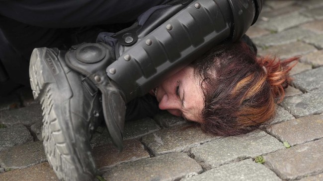 FILE - In this May 26, 2019, file photo, police detain a woman during a yellow vest protest with other groups in Brussels. The death of George Floyd has renewed scrutiny of immobilization techniques long used in policing around the world. (AP Photo/Francisco Seco, File)