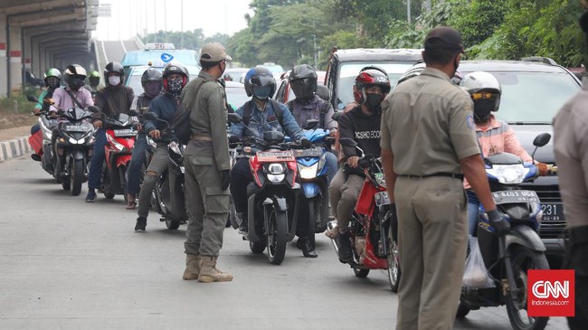 Petugas gabungan memeriksa kelengkapan surat pengendara yang akan masuk wilayah Jakarta terkait penerapan PSBB Transisi, Jakarta, Jumat, 5 Juni 2020. Direktorat Lalu Lintas Polda Metro Jaya tetap melakukan pemeriksaan pelanggaran pembatasan sosial berskala besar (PSBB) di 67 titik di wilayah DKI Jakarta selama masa transisi.CNNIndonesia/Safir Makki