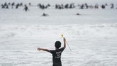 Penghormatan Para Surfer untuk George Floyd Nathan Rangel, 11, jumps in the water carrying a rose as surfers participate in a paddle out ceremony at