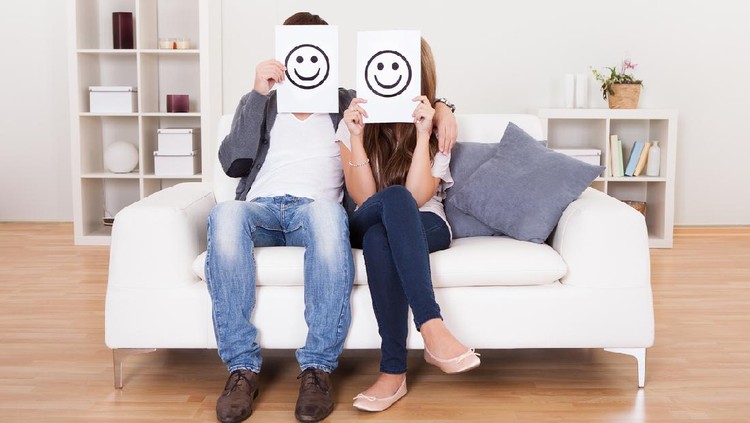 Couple covered faces with smiley white paper.