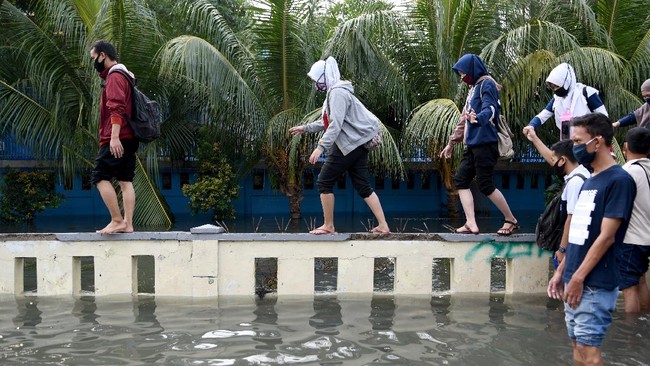 Warga meniti pagar menghindari banjir air rob di kawasan Muara Baru, Penjaringan, Jakarta Utara, Jumat (5/6/2020). Menurut Badan Meteorologi, Klimatologi, dan Geofisika (BMKG) rob disebabkan oleh kondisi pasang air laut yang cukup tinggi di beberapa wilayah Indonesia akibat fase bulan purnama. ANTARA FOTO/M Risyal Hidayat/wsj.