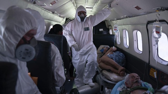 Nurse Janete Vieira, center, and Doctor Daniel Siqueira monitor COVID-19 patients onboard an aircraft as they are transferred from Santo Antônio do Içá to a hospital in Manaus, Brazil, Tuesday, May 19, 2020. The virus has spread upriver from Manaus, creeping into remote riverside towns and indigenous territories to infect indigenous tribes. (AP Photo/Felipe Dana)
