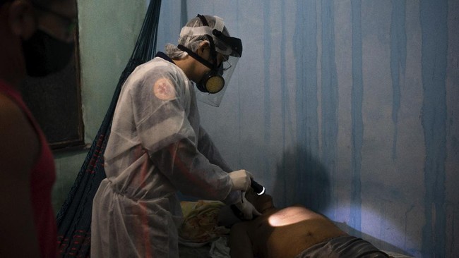An ambulance doctor checks for the pulse of an elderly man who had just died at his home amid the new coronavirus pandemic in Manaus, Brazil, Thursday, May 21, 2020. Per capita, Manaus is Brazil's major city hardest hit by COVID-19. (AP Photo/Felipe Dana)