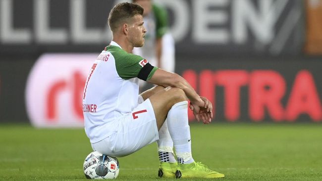 Augsburg's Florian Niederlechner sits on the ground after the German Bundesliga soccer match between FC Augsburg and SC Paderborn 07 in Augsburg, Germany, Wednesday, May 27, 2020. The German Bundesliga is the world's first major soccer league to resume after a two-month suspension because of the coronavirus pandemic. (Matthias Hangst/Pool via AP)