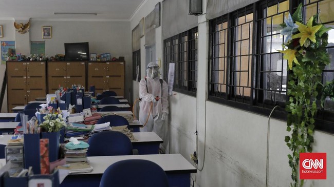 Anggota Palang Merah Indonesia menyemprotkan desinfektan dalam upaya menahan penyebaran virus corona di dalam ruang kelas di SMPN 139 dan SDN Malaka Jaya 04 Pagi. Jakarta, Selasa, 9 Juni 2020. (CNN Indonesia/ Adhi Wicaksono)
