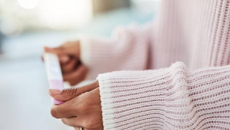 Young woman looking miserable staring at pregnancy test