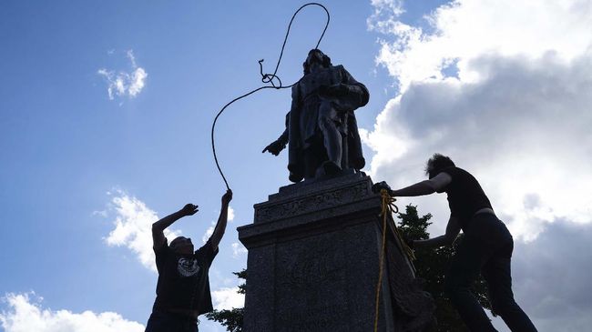 Mike Forcia, left, and another man fasten ropes around the neck of a statue of Christopher Columbus at the Minnesota state Capitol in St. Paul, Minn., Wednesday, June 10, 2020. (Evan Frost/Minnesota Public Radio via AP)