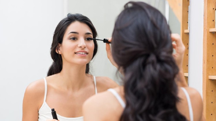 Woman applying black mascara on eyelashes with makeup brush. Young beautiful woman applying mascara makeup on eyes at bathroom. Beautiful brunette girl applying makeup on eyes in the morning time.