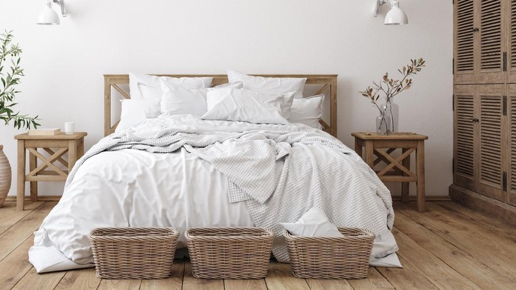 Patterned pouf and basket in bright bedroom interior with lamps, plants and poster next to bed. Real photo