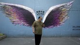 Nyalang Edisi 13 Juni 2020 A man stands in front of graffiti on a wall in Beijing on June 5, 2020. (Photo by WANG Zhao / AFP)