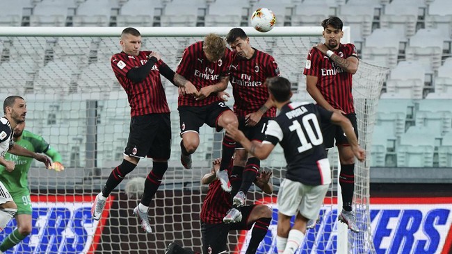 Juventus' Paulo Dybala performs a free-kick past AC Milan's wall , during an Italian Cup second leg soccer match between Juventus and AC Milan at the Allianz stadium, in Turin, Italy, Friday, June 12, 2020. The match was being played without spectators because of the coronavirus lockdown. (Spada/LaPresse via AP)