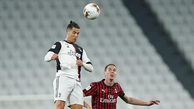 Juventus' Cristiano Ronaldo heads the ball past AC Milan's Andrea Conti during an Italian Cup second leg soccer match between Juventus and AC Milan at the Allianz stadium, in Turin, Italy, Friday, June 12, 2020. The match was being played without spectators because of the coronavirus lockdown. (Spada/LaPresse via AP)