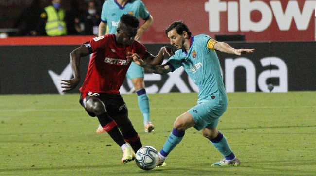 Barcelona's Lionel Messi, right, vies for the ball with Marllorca's Iddrisu Mohamed Baba during the Spanish La Liga soccer match between Mallorca and FC Barcelona at Son Moix Stadium in Palma de Mallorca, Spain, Saturday, June 13, 2020. With virtual crowds, daily matches and lots of testing for the coronavirus, soccer is coming back to Spain. The Spanish league resumes this week more than three months after it was suspended because of the COVID-19 pandemic. (AP Photo/Francisco Ubilla)