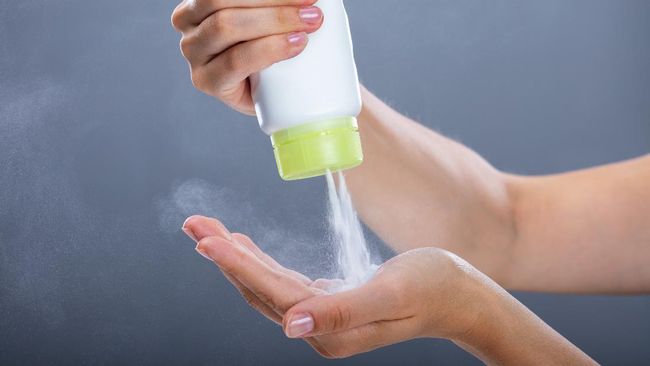 Woman's Hand Using Talcum Powder On Grey Background