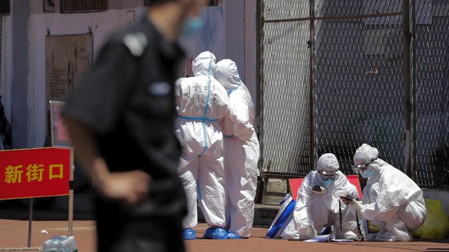Workers in protective suits check on people's names in a list at a stadium in Beijing, Sunday, June 14, 2020. China is reporting its highest daily total of coronavirus cases in two months after the capital's biggest wholesale food market was shut down following a resurgence in local infections. (AP Photo/Andy Wong)