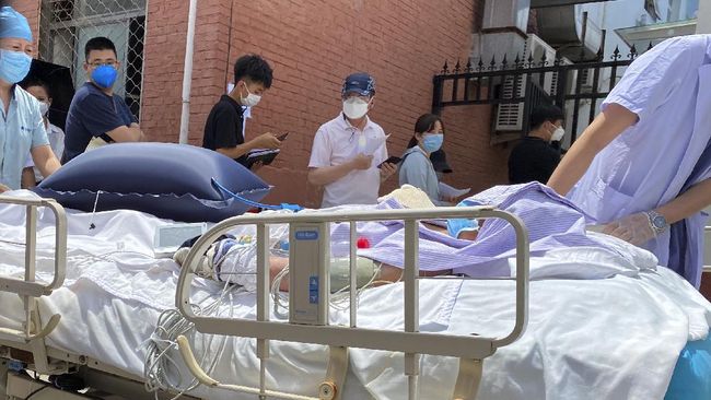 A patient is pushed past a line of residents waiting to be tested at a fever clinic in Beijing on Monday, June 15, 2020. China's capital was bracing Monday for a resurgence of the coronavirus after more than 100 new cases were reported in recent days in a city that hadn't seen a case of local transmission in more than a month. (AP Photo/Ng Han Guan)