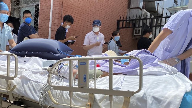 A patient is pushed past a line of residents waiting to be tested at a fever clinic in Beijing on Monday, June 15, 2020. China's capital was bracing Monday for a resurgence of the coronavirus after more than 100 new cases were reported in recent days in a city that hadn't seen a case of local transmission in more than a month. (AP Photo/Ng Han Guan)