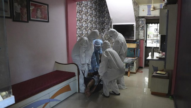 In this May 28, 2020 photo, Izhaar Hussain Shaikh, front left, an ambulance driver who works for HelpNow, an initiative to help the stretched services of first responders, along with his helpers picks up a COVID-19 patient from his home in Mumbai, India. It's an exhausting job and Shaikh's daily shifts are grueling, sometimes even stretching to 16 hours. For a city that has a history of shortage of ambulances and where coronavirus pandemic has claimed hundreds of lives, putting the health care system under immense strain, every help counts. (AP Photo/Rafiq Maqbool)