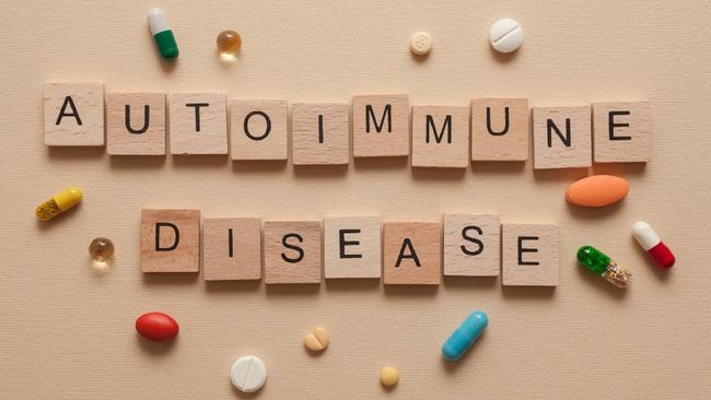 The word autoimmune disease formed with wooden letters and pills around