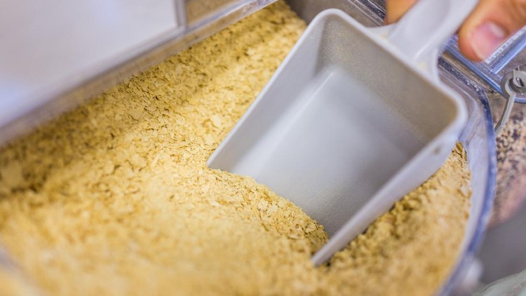 Person scooping nutritional yeast from bulk section