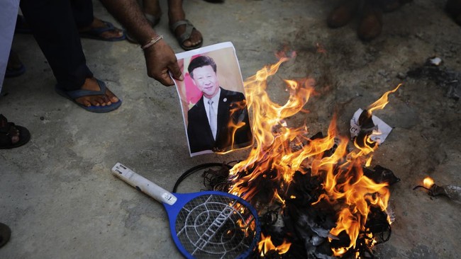 An Indian man burns a photograph of Chinese president Xi Jinping during a protest against China in Ahmedabad, India, Tuesday, June 16, 2020. At least three Indian soldiers, including a senior army officer, were killed in a confrontation with Chinese troops along their disputed border high in the Himalayas where thousands of soldiers on both sides have been facing off for over a month, the Indian army said Tuesday. (AP Photo/Ajit Solanki)