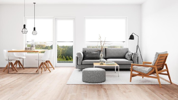 Posters on grey wall above white cupboard in bright living room interior with sofa and carpet. Real photo