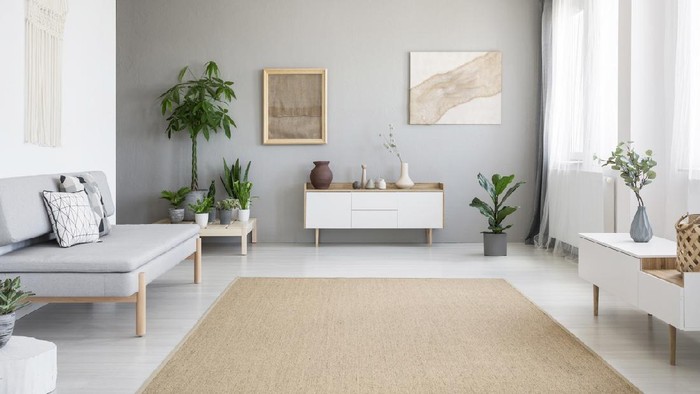 Posters on grey wall above white cupboard in bright living room interior with sofa and carpet. Real photo