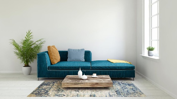 Posters on grey wall above white cupboard in bright living room interior with sofa and carpet. Real photo