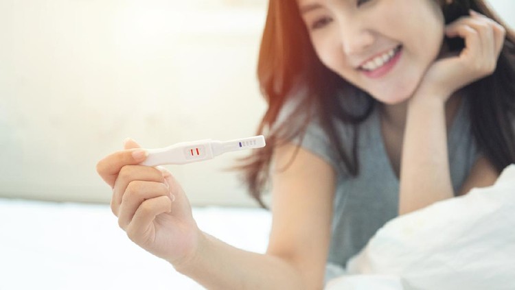 Tes Kehamilan Selective focus on tester.Expecting mom with cheerful face with pregnancy in hand.