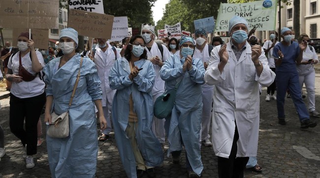 Hospital workers attend a demonstration Tuesday, June 16, 2020 in Paris. French hospital workers and others are protesting in cities around the country to demand better pay and more investment in France's public hospital system, which is considered among the world's best but struggled to handle a flux of virus patients after years of cost cuts. France has seen nearly 30,000 virus deaths. (AP Photo/Christophe Ena)