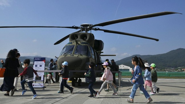 Children walk in front of a South Korea KUH-1 Surion helicopter during a preview of the Seoul International Aerospace and Defense Exhibition at a military air base in Seongnam, south of Seoul, on October 14, 2019. - The exhibition will run from October 15 to 20 with 430 companies from 34 countries taking part. (Photo by Jung Yeon-je / AFP)