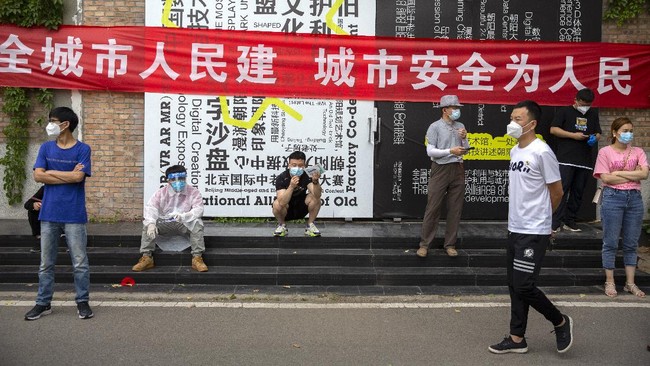 People wait outside a COVID-19 testing site after they were ordered by the government to be tested after potentially being exposed to the coronavirus outbreak at a wholesale food market in Beijing, Wednesday, June 17, 2020. As the number of cases of COVID-19 in Beijing climbed in recent days following an outbreak linked to a wholesale food market, officials announced they had identified hundreds of thousands of people who needed to be tested for the coronavirus. (AP Photo/Mark Schiefelbein)