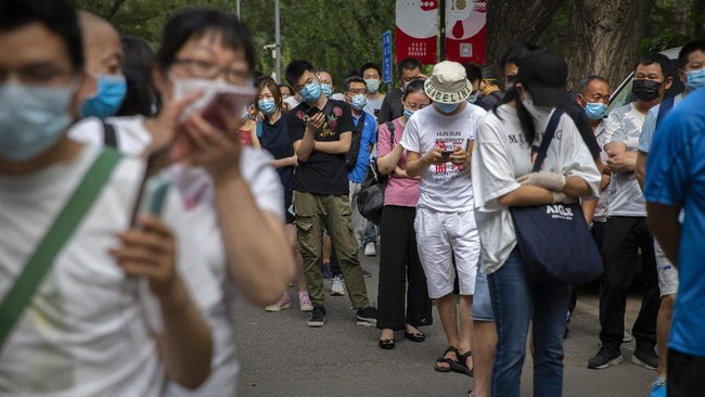 People wait in line at a COVID-19 testing site after they were ordered by the government to be tested after potentially being exposed to the coronavirus outbreak at a wholesale food market in Beijing, Wednesday, June 17, 2020. As the number of cases of COVID-19 in Beijing climbed in recent days following an outbreak linked to a wholesale food market, officials announced they had identified hundreds of thousands of people who needed to be tested for the coronavirus. (AP Photo/Mark Schiefelbein)