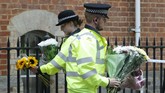 Teror Penusukan di Inggris Police officers collect flowers left at the Abbey gateway of Forbury Gardens following a multiple stabbing attack which took place on Saturday, in Reading, England, Sunday June 21, 2020. Police say a stabbing rampage in Britain that killed three people as they sat in a park on a summer evening is being considered a terrorist attack. A 25-year-old man believed to be the lone attacker is in custody. (AP Photo/Alastair Grant)