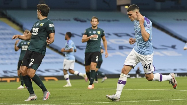 Manchester City's Phil Foden, right, celebrates after scoring his teams fifth goal during the English Premier League soccer match between Manchester City and Burnley at Etihad Stadium, in Manchester, England, Monday, June 22, 2020. (AP Photo/Michael Regan,Pool)